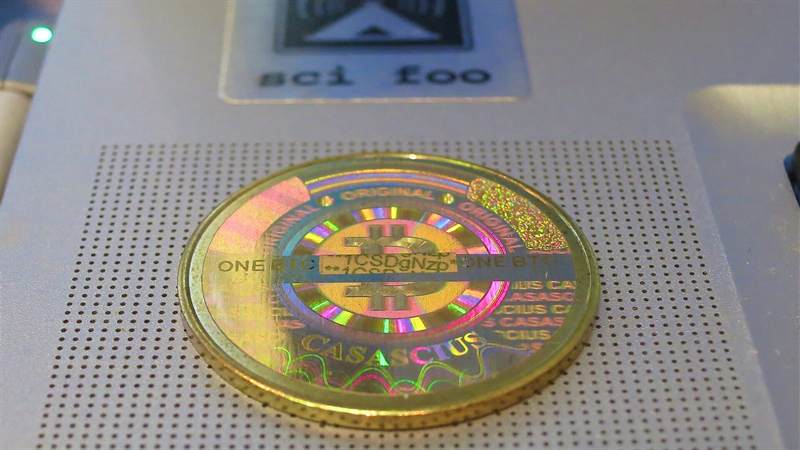 Physical Casascius bitcoin coin on a laptop speaker grille