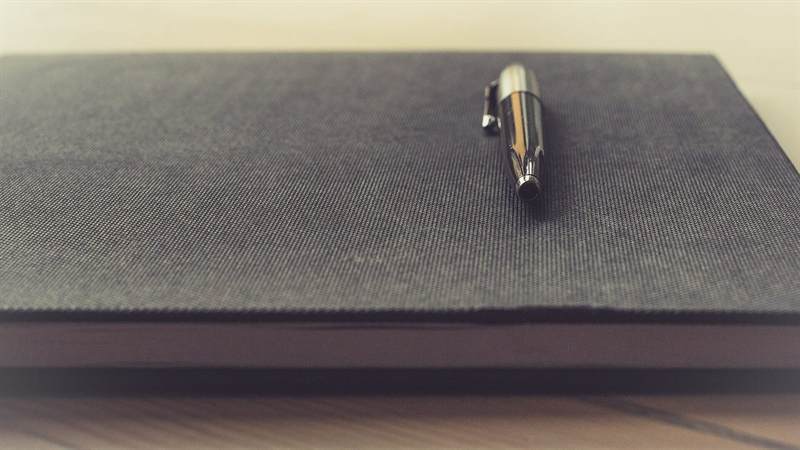 Closed notebook with a pen on the cover