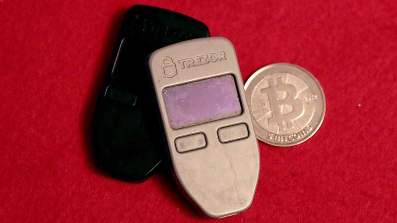 Hardware wallets next to a physical bitcoin coin